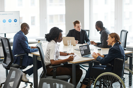 Woman in wheelchair sits at the table with other employees