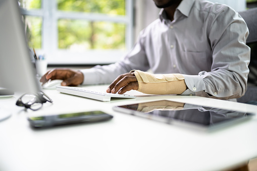 Person typing on a keyboard with arm brace filling out workers' compensation