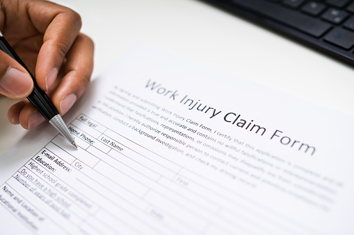 person filling out worker injury compensation claim form.