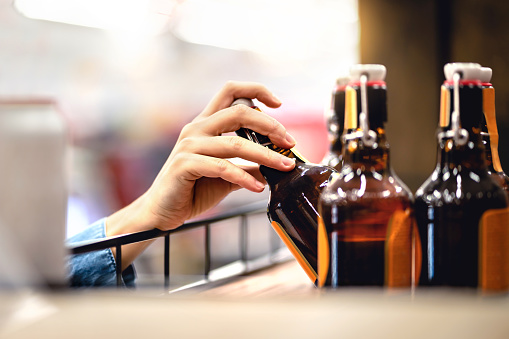 A person pulling a liquor botte out of the fridge.