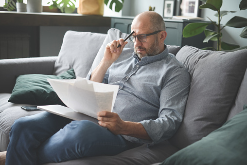 Man sitting on couch looking over bankruptcy papers