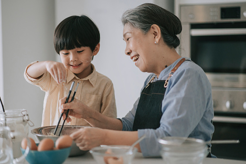 Grandparent helping grandchild with cooking skills