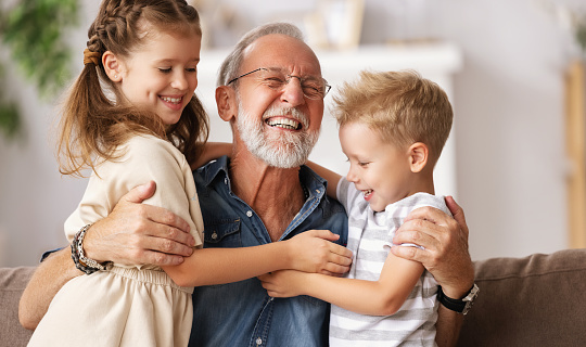 Two children visiting their grandfather and hugging