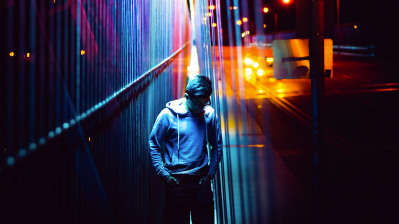 Man standing on the edge of a roped bridge at night