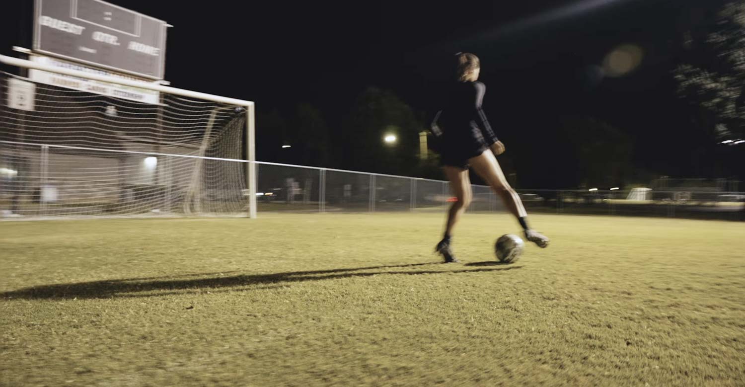 Woman kicking a soccer ball into a goal