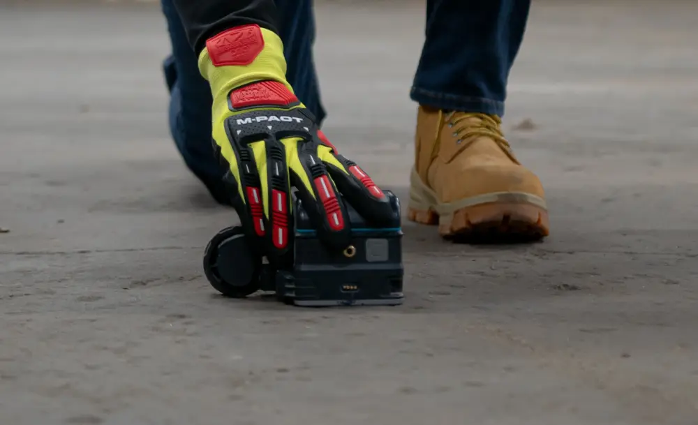 A hand holding a ground penetrating radar concrete scanning antenna.