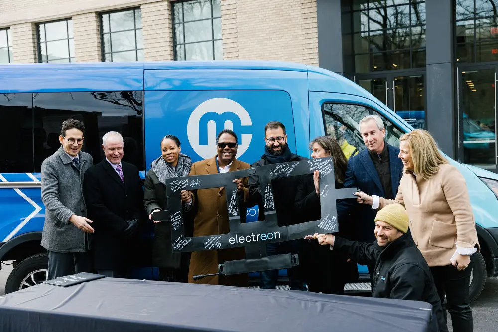 People pose for a photo in front of an electric van.