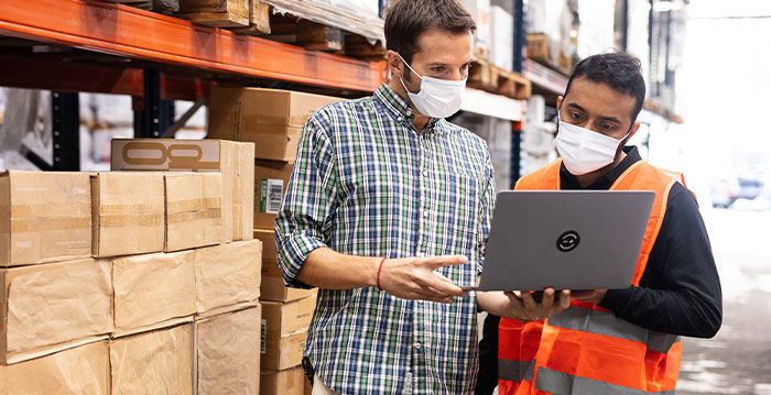 Two warehouse workers looking at inventory on a laptop computer to plan for inventory.