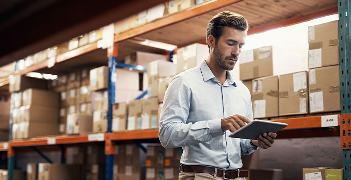 An image of a man in a warehouse tracking inventory with a tablet.