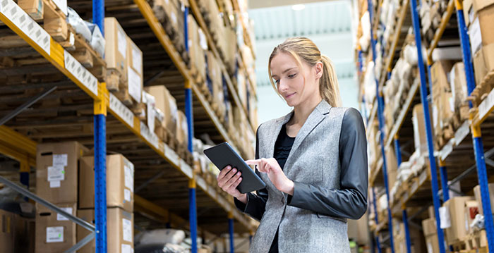 A woman using a multichannel inventory management software in a warehouse.