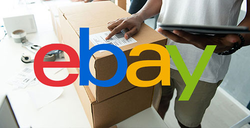 The eBay logo with boxes behind the logo and a man pointing to the label on the box.