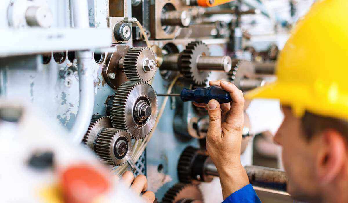 Close-up of the hands and face of a person servicing a gear