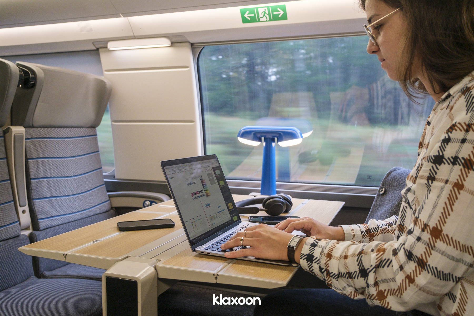 Dans un train, une femme travaille sur le Board Klaxoon.