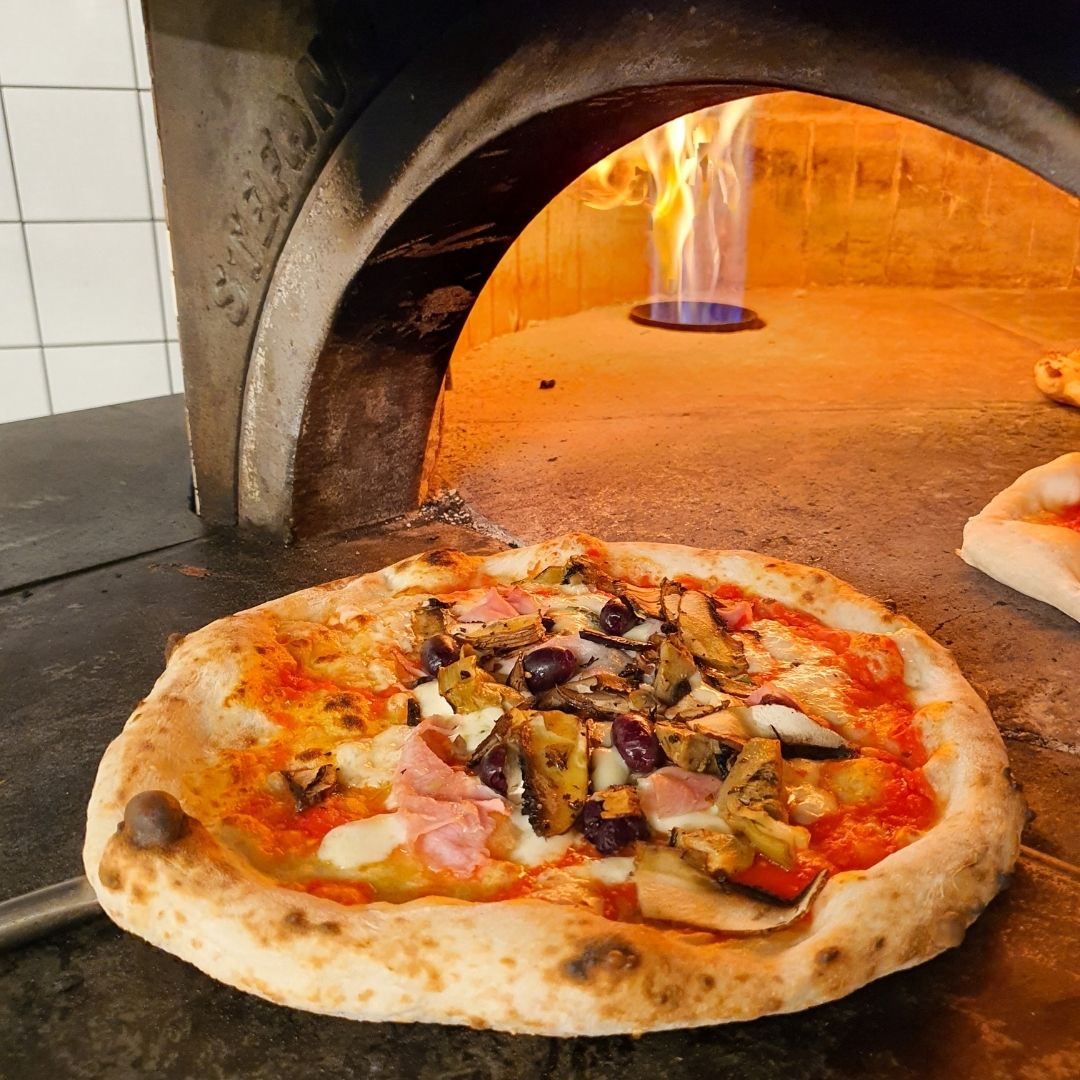 picture of pizza being pushed into an oven