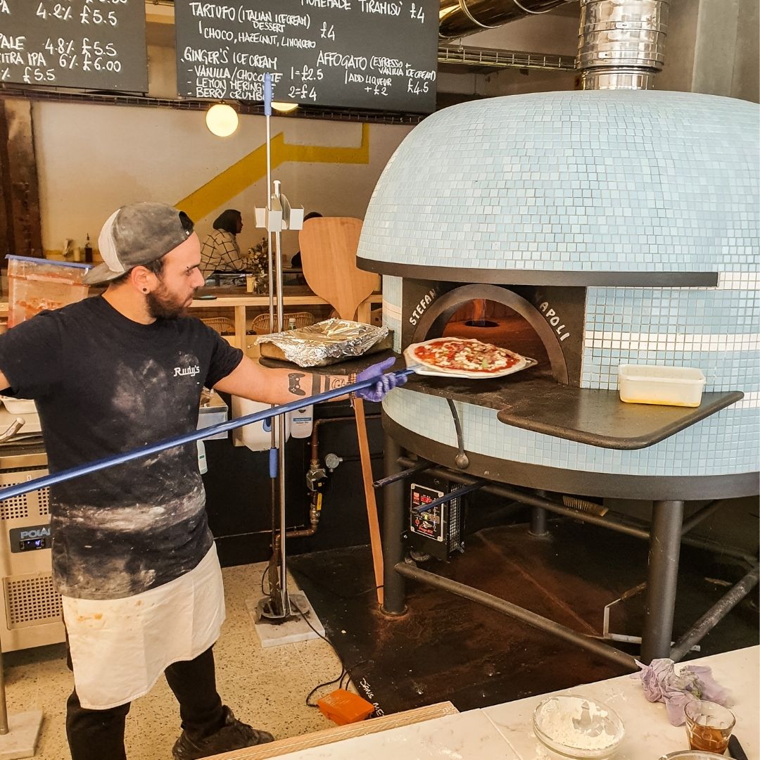 picture of pizzaiolo putting a pizza in the oven