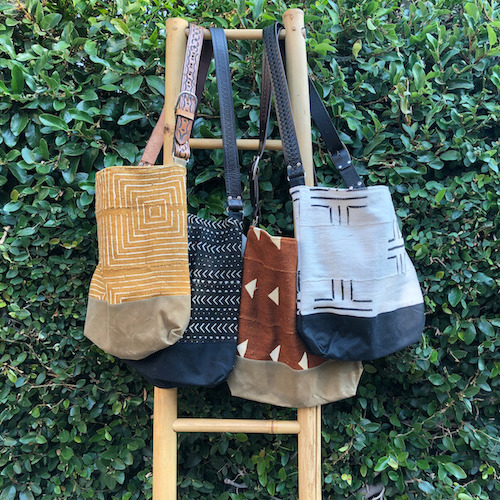 Assorted Jenna Bee handmade African Mudcloth tote bags hanging on a ladder