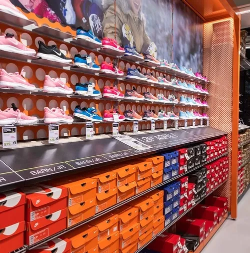 In store shelves filled with shoes on the top and shoe boxes in the lower part. Photo.