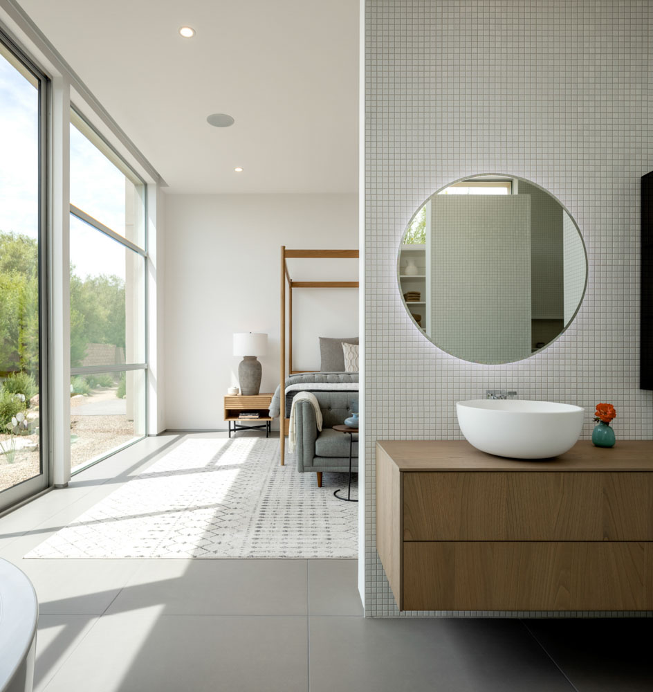 A modern minimalist residential bedroom with neutral colors professionally styled with a vanity in the foreground captured during the day with natural light.