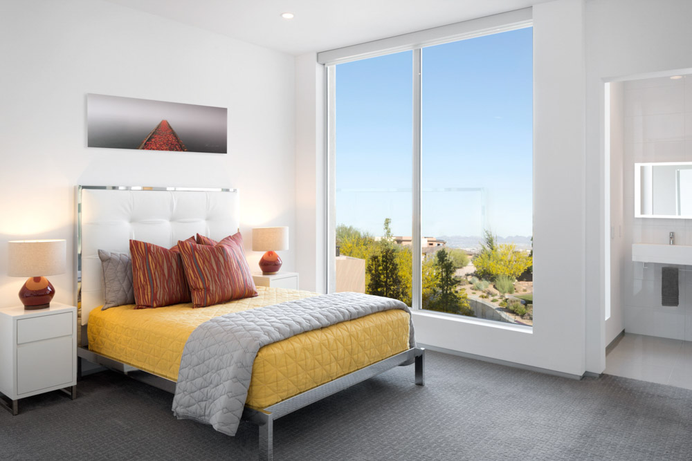 A modern minimalist residential guestroom in a home professionally styled with vibrant decor and artwork during the day lit by natural light.