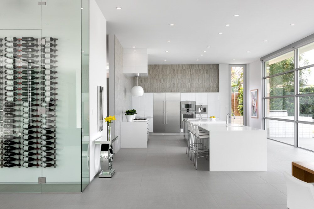A modern minimalist residential kitchen with neutral colors, contemporary furniture, artwork and a wine cellar shot during the day with natural light.