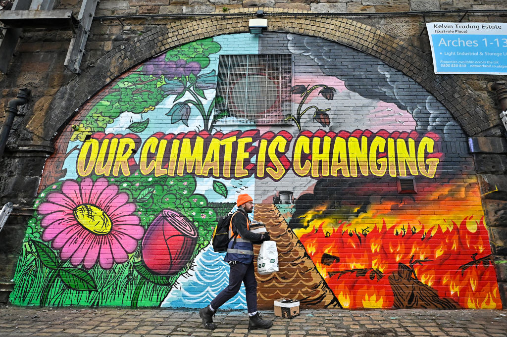 Artists paint a 'our climate is changing' mural on a wall next to the SEC in Glasgow, which hosts COP26 