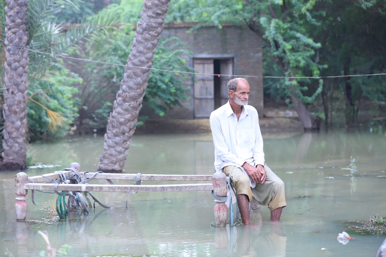 Old man surrounded by flood water - Image from AMWT