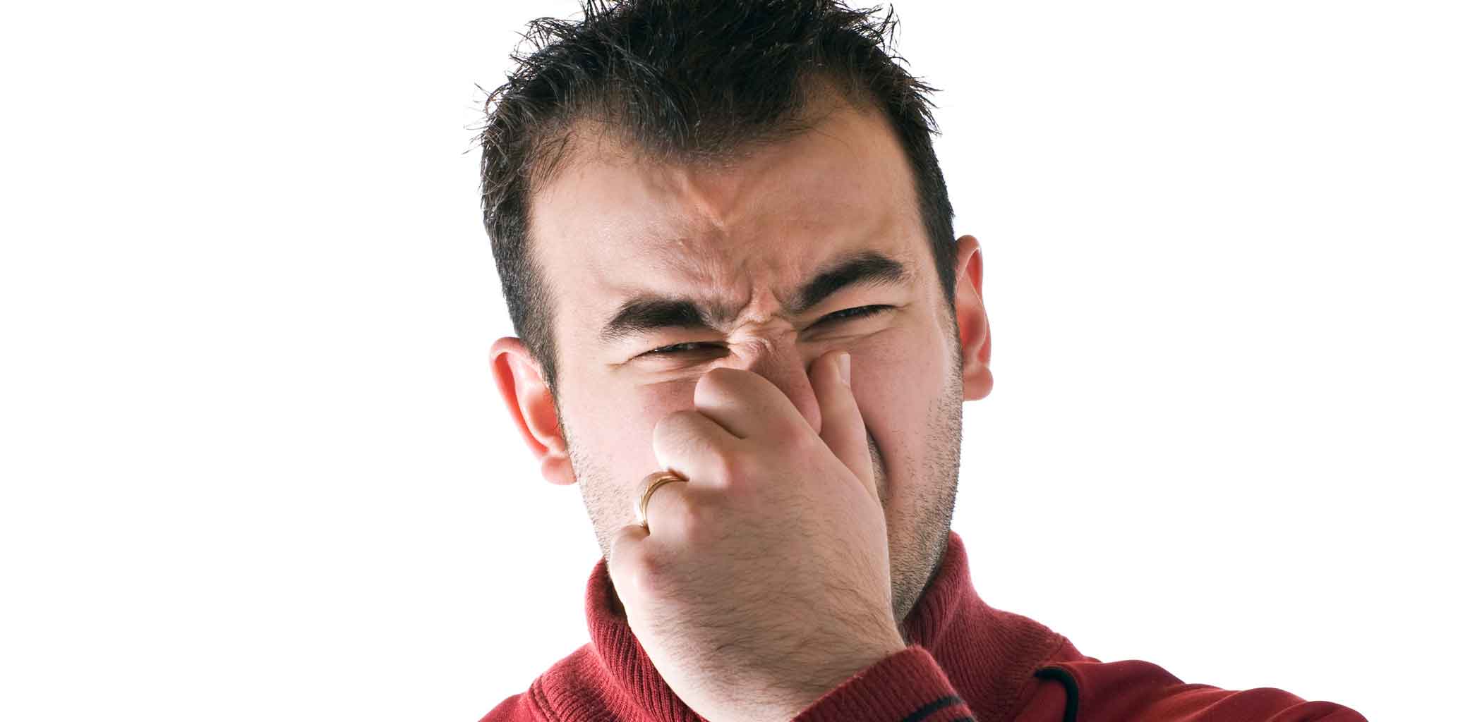 Парень закрывает себе рот рукой на светлом фоне. Мужчина вызывает отвращение. Плохой запах. Мужчина вызывает отвращение. A man covers his mouth.