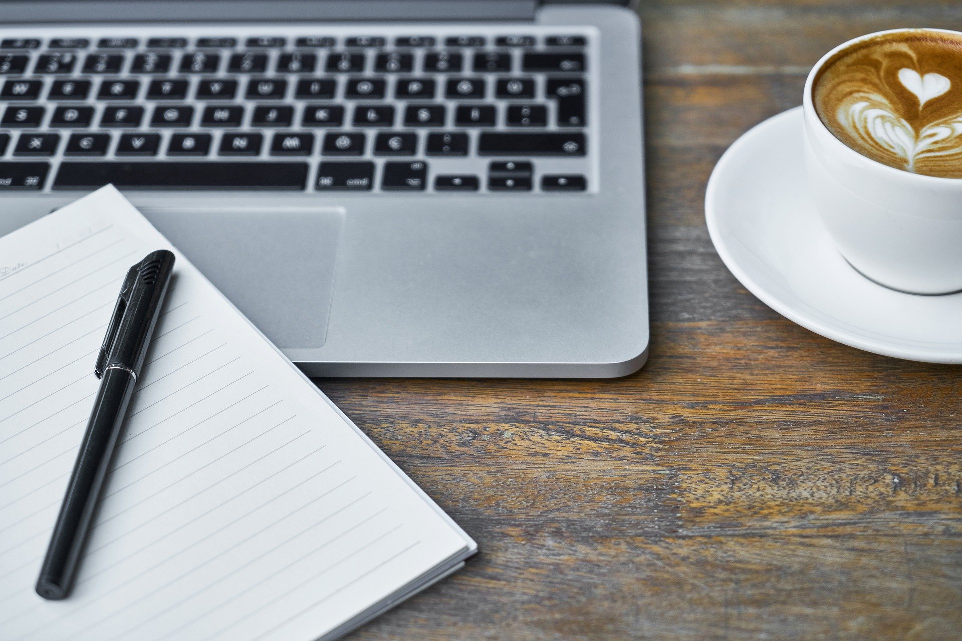 Notepad, laptop and coffee on a desk