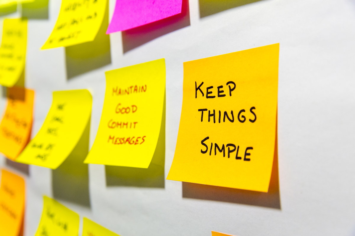 Post-it notes stuck to a wall, with the main one in focus reading 'Keep it simple'