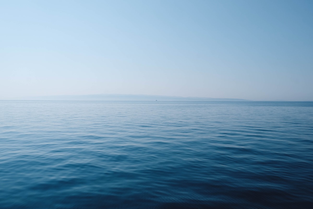 The sea viewed from an angle. The sea is deep blue and the sky is blue too. It is calm.