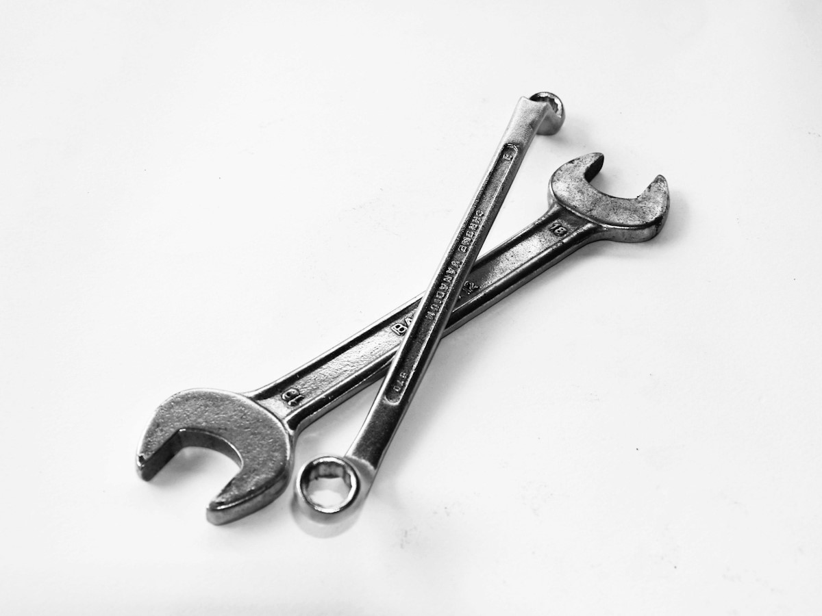 Two chrome spanners laid across one another on a white background.