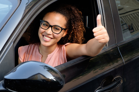 Happy young woman seated in her new car