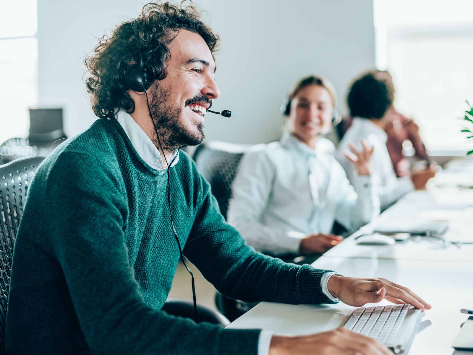 Man sitting at office desk answering customer support calls