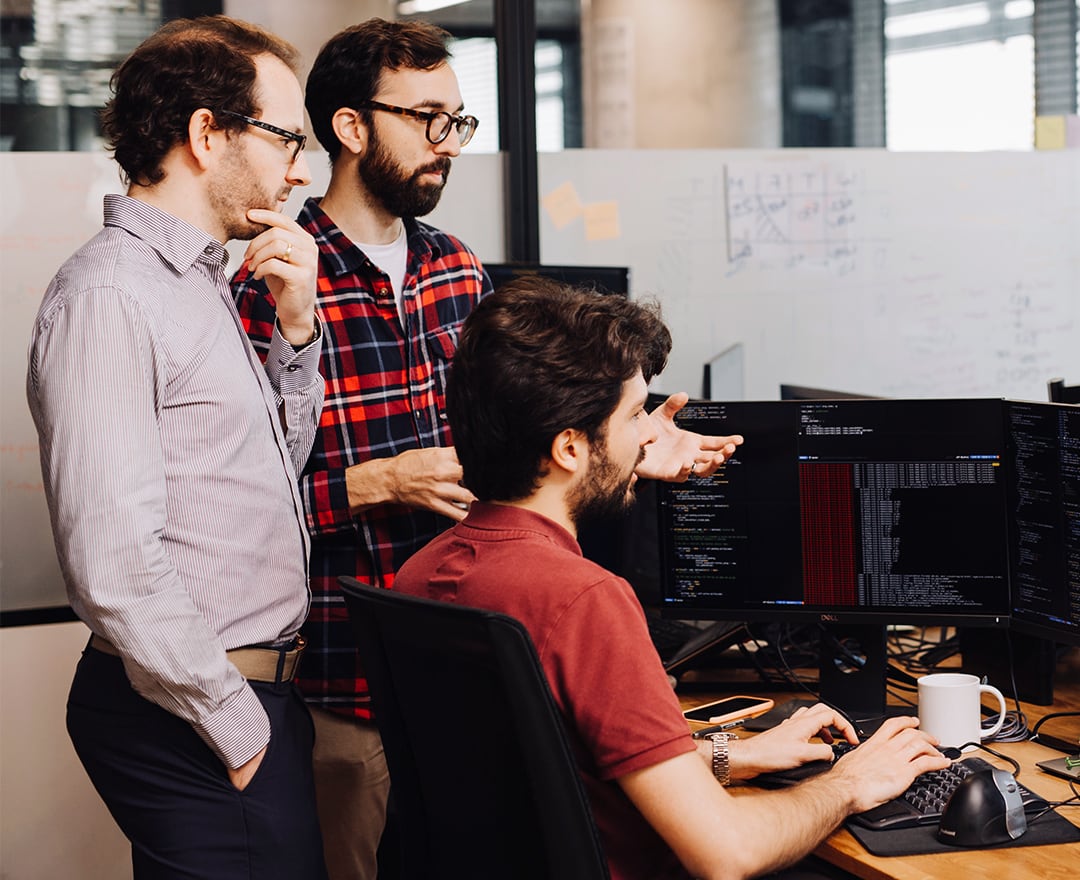 Colleagues looking at screen code in office