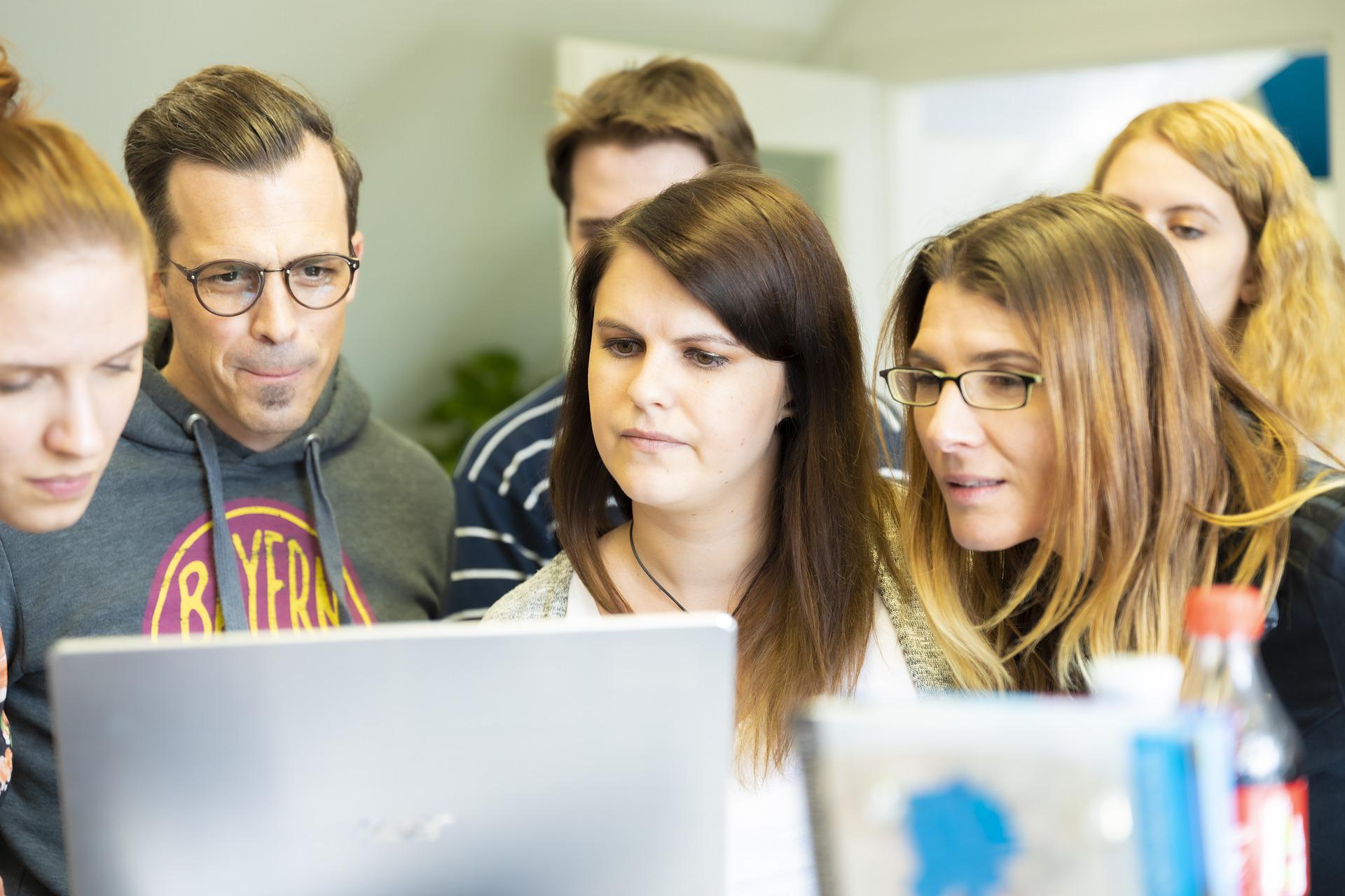 Team members looking at a computer screen with expressions of doubt and uncertainty
