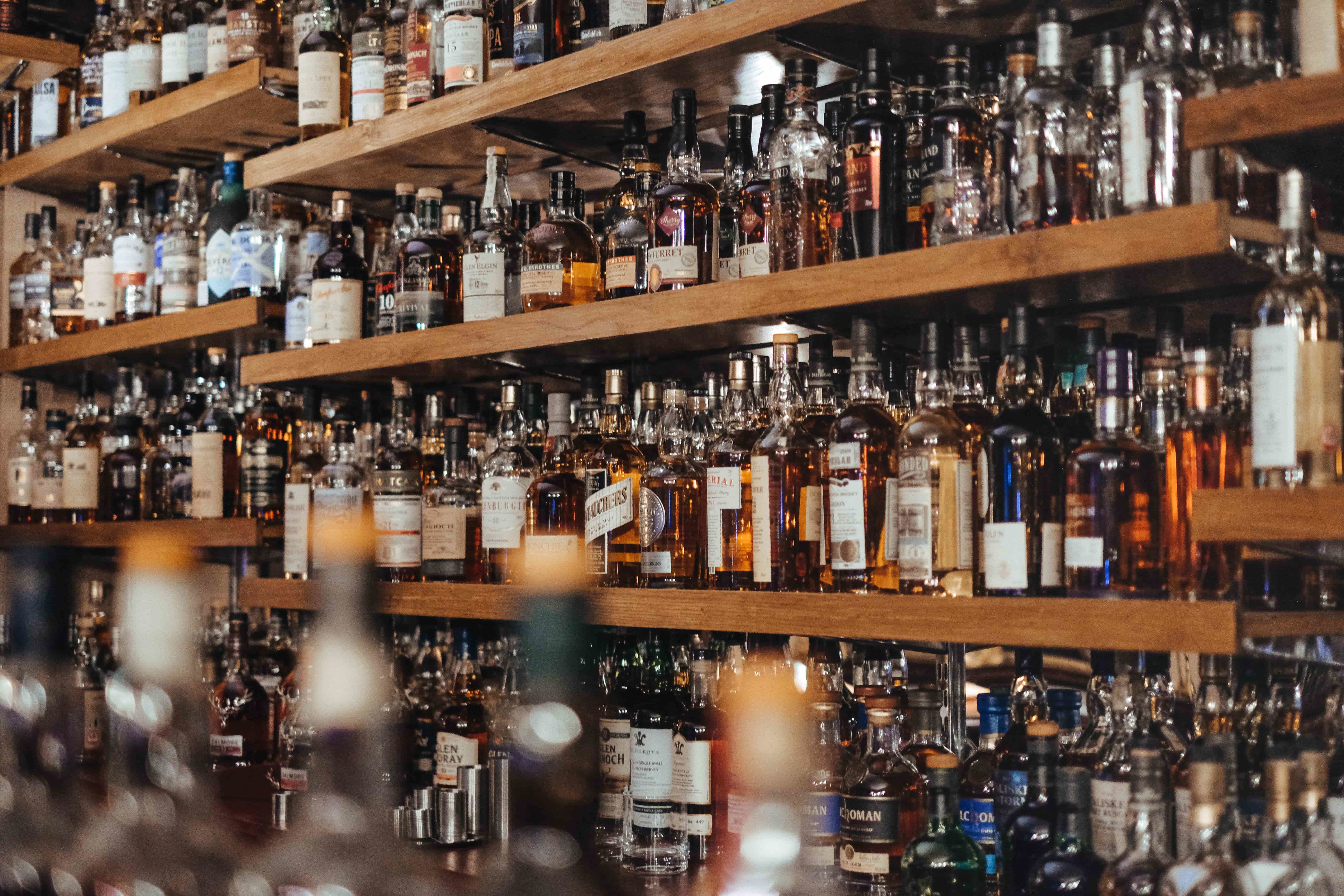 A lot of liquor bottles lined up on a bar