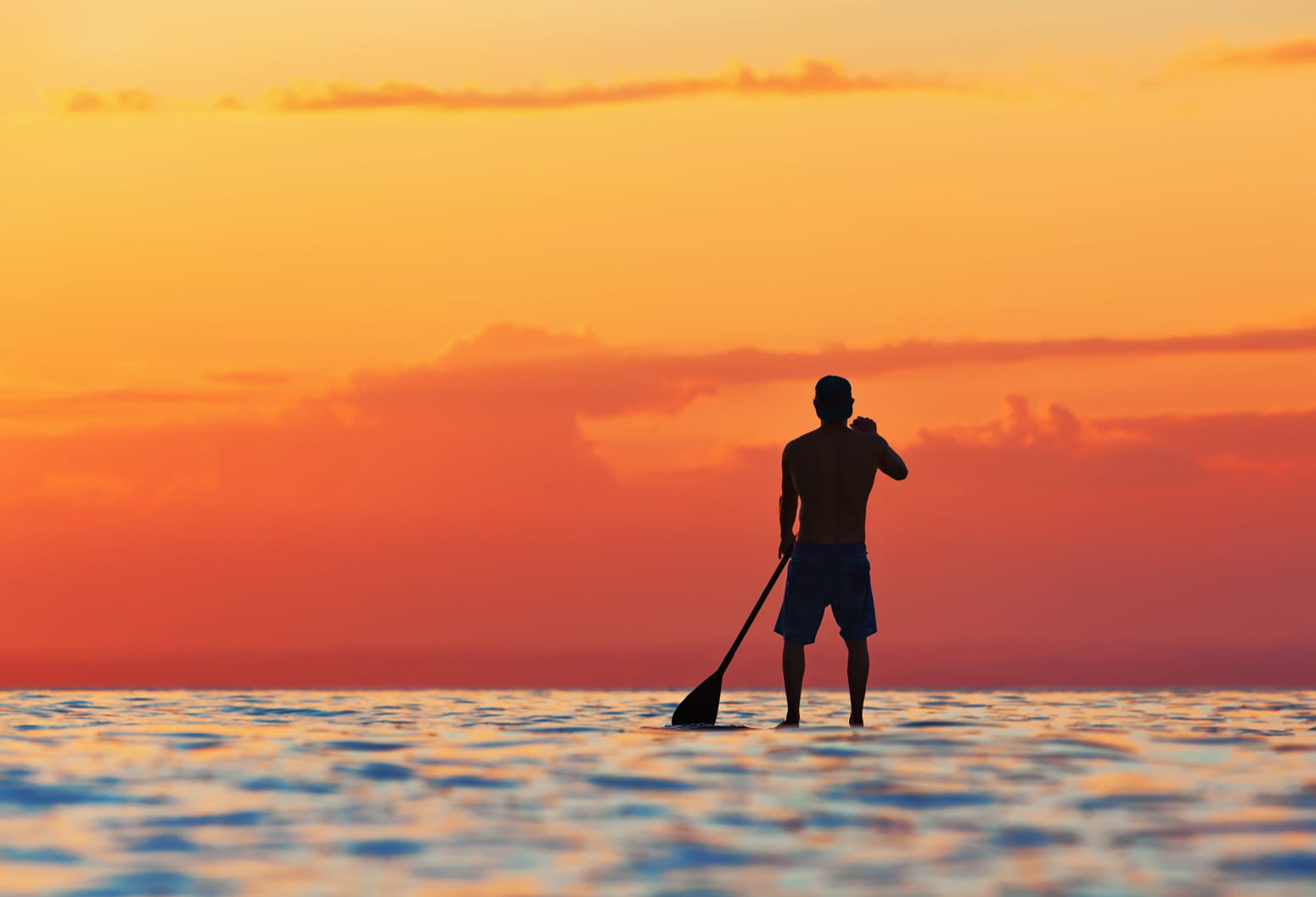 Hawaiian man on a stand up paddle board in the twilight hours