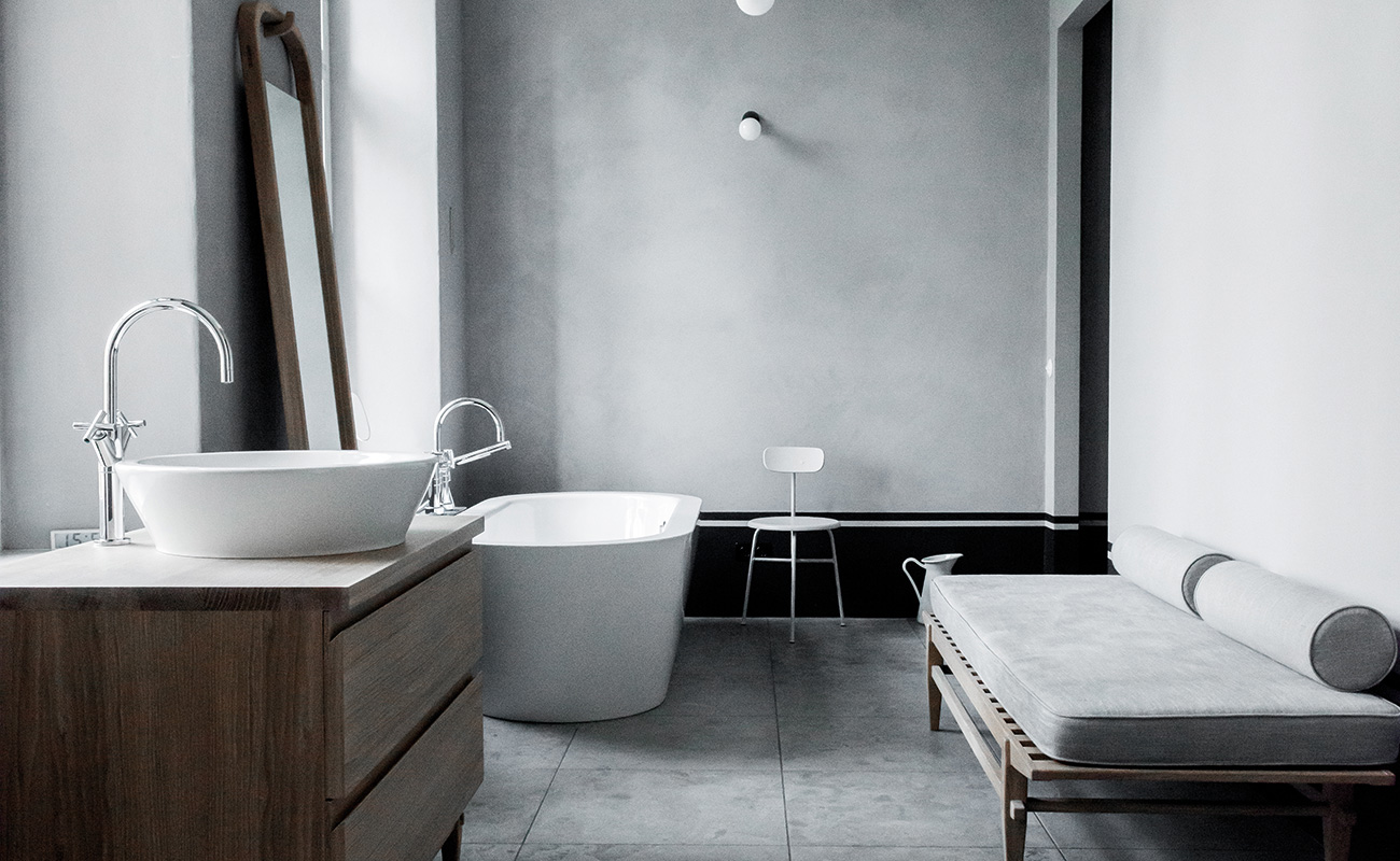 A bathroom with grey tiles and free standing bathtub