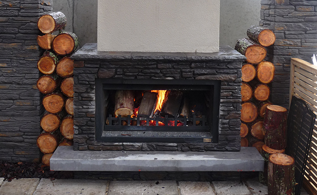 Черный камень, деревянный камин с горящим огнем.