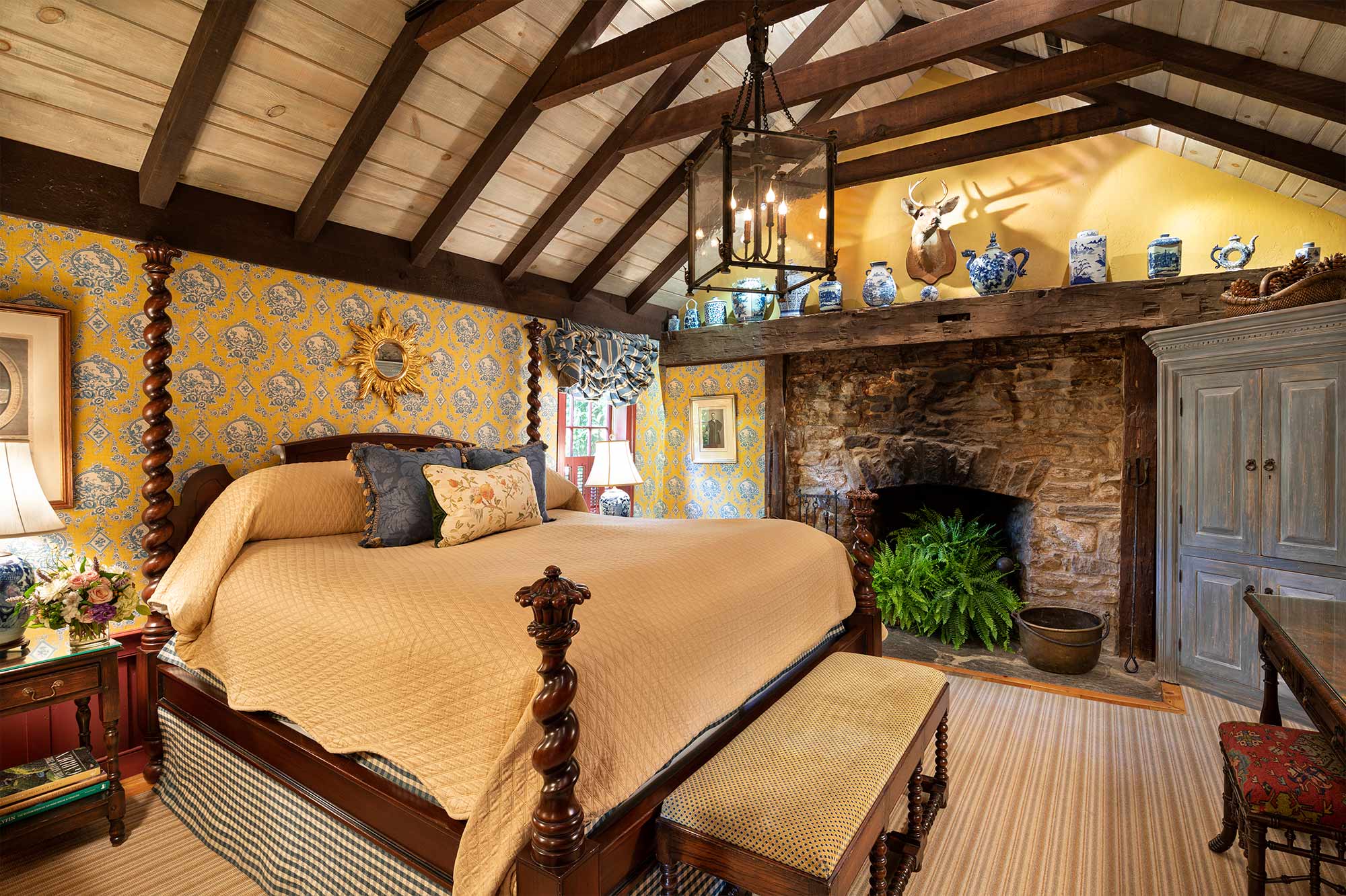 A large master bedroom with a king sized bed and large, stone fireplace.