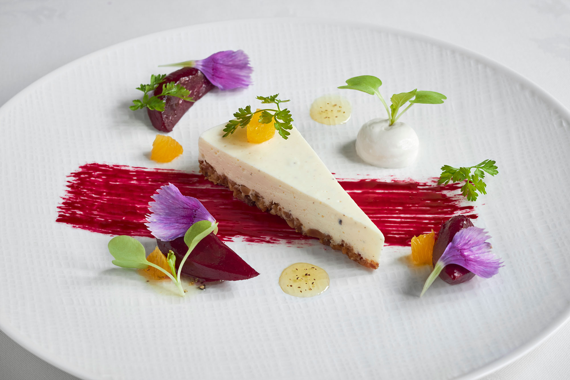 Dessert displayed on a white plate with colorful garnishes of vibrant purples, oranges and greens.