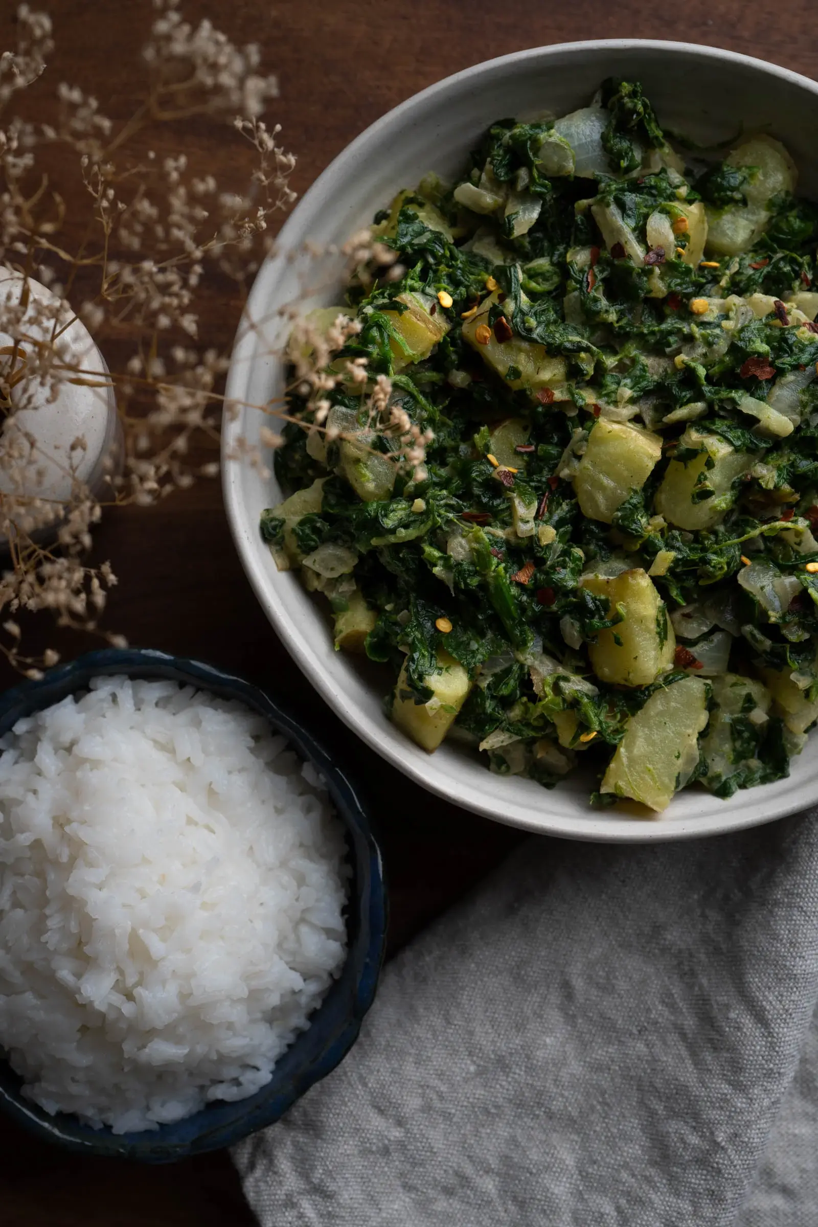 Bowl of Saag Aloo next to a bowl of rice. 