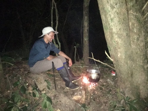 Image of AJ tending to a pot in the Amazon forest