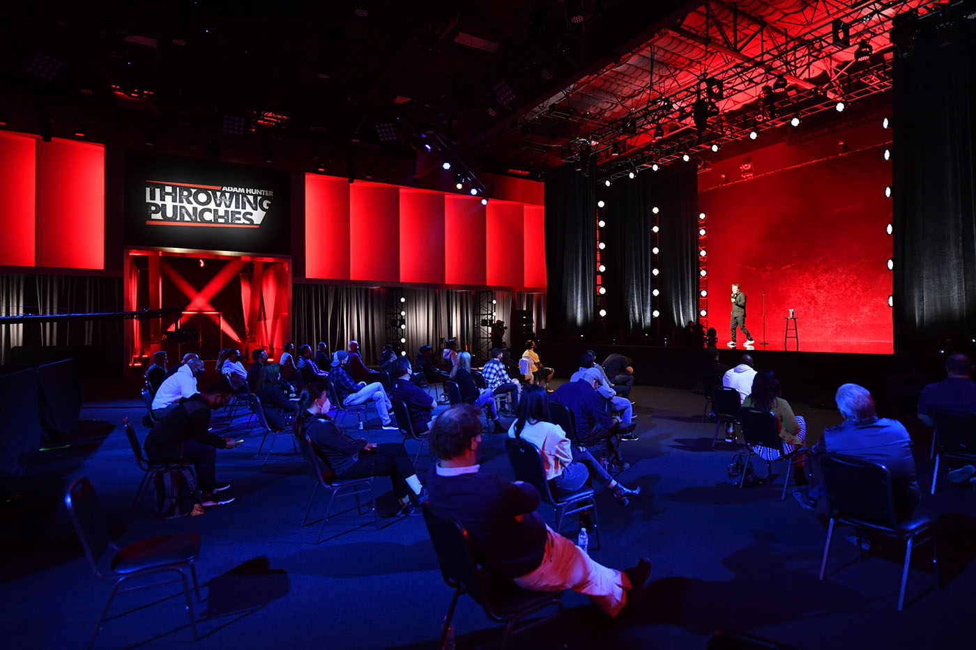 Stage set up in front of a live crowd with ambient red lighting