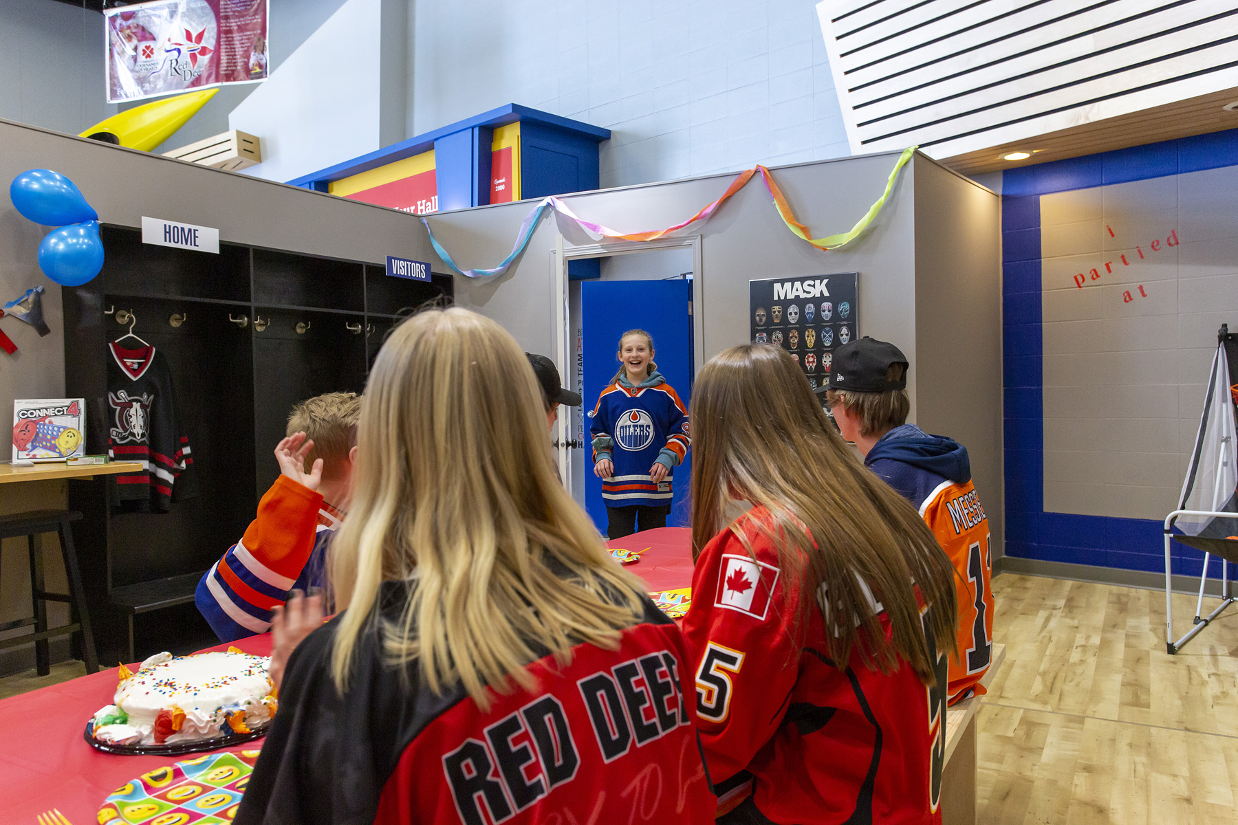 Kids of different ages wearing hockey jerseys enjoying the birthday room at the Alberta Sports Hall of Fame