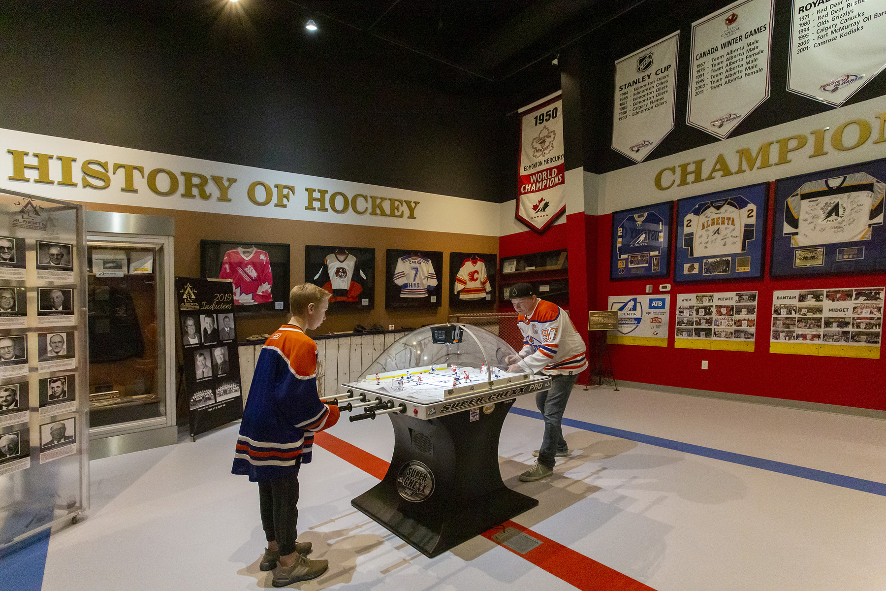 Kids in hockey jerseys playing bubble hockey in the Alberta Hockey Hall of Fame at the Alberta Sports Hall of Fame