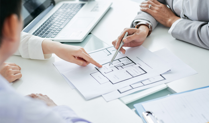 a group of professionals observe a floorplan pointing out key elements of the facility