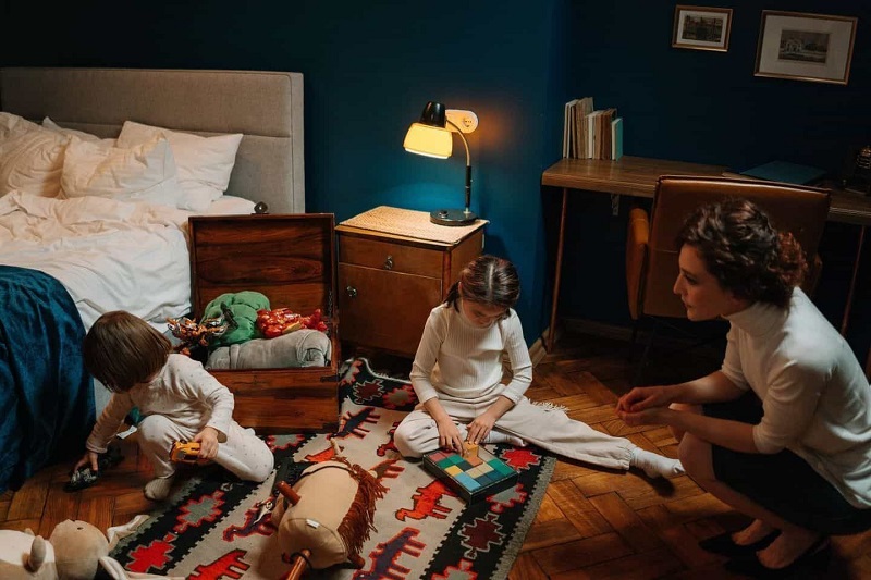 The kids are playing at a bedroom with their toys