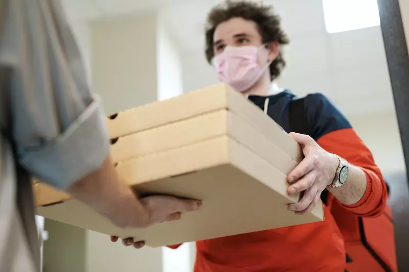 A delivery boy giving parcel to another man