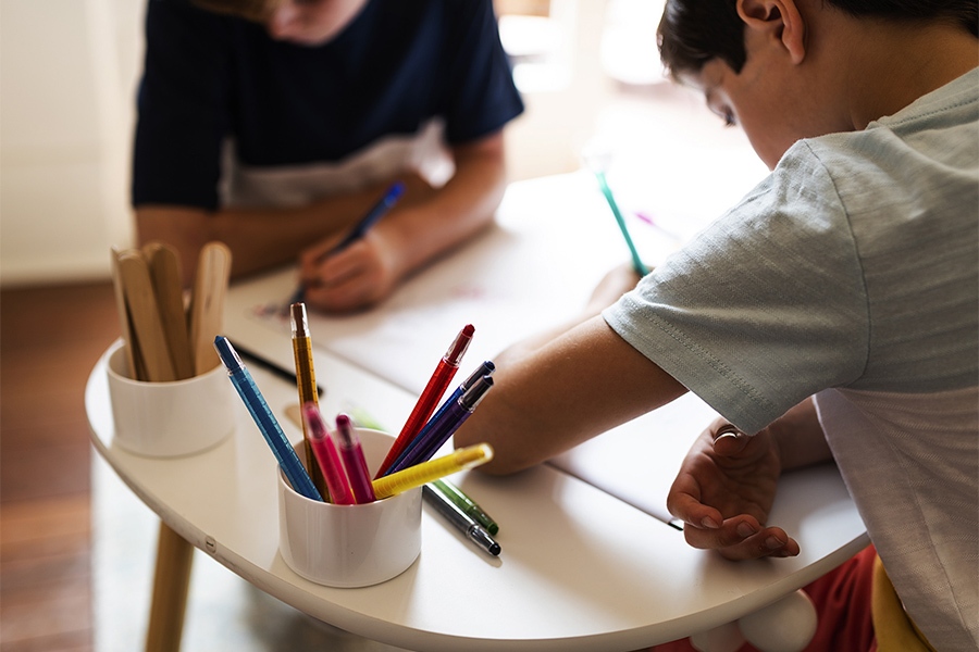 Young boys drawing and colouring in kids reading corner
